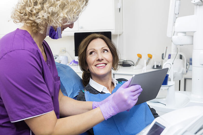 Middle-aged woman smiling as she talks to a hygienist