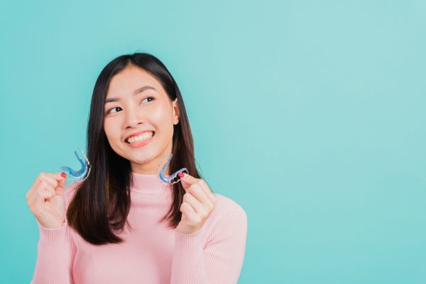 woman holding two invisalign aligners