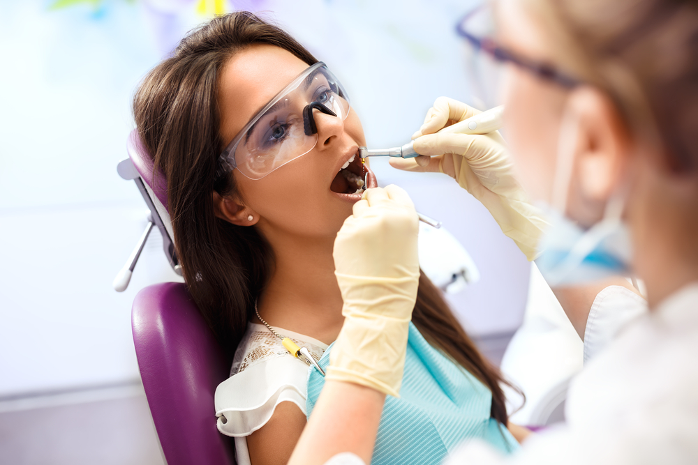 dentist using dental laser on female patient's teeth